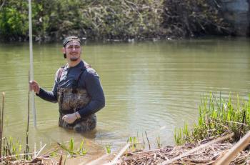 A student earning a degree in environmental science taking samples from a river.